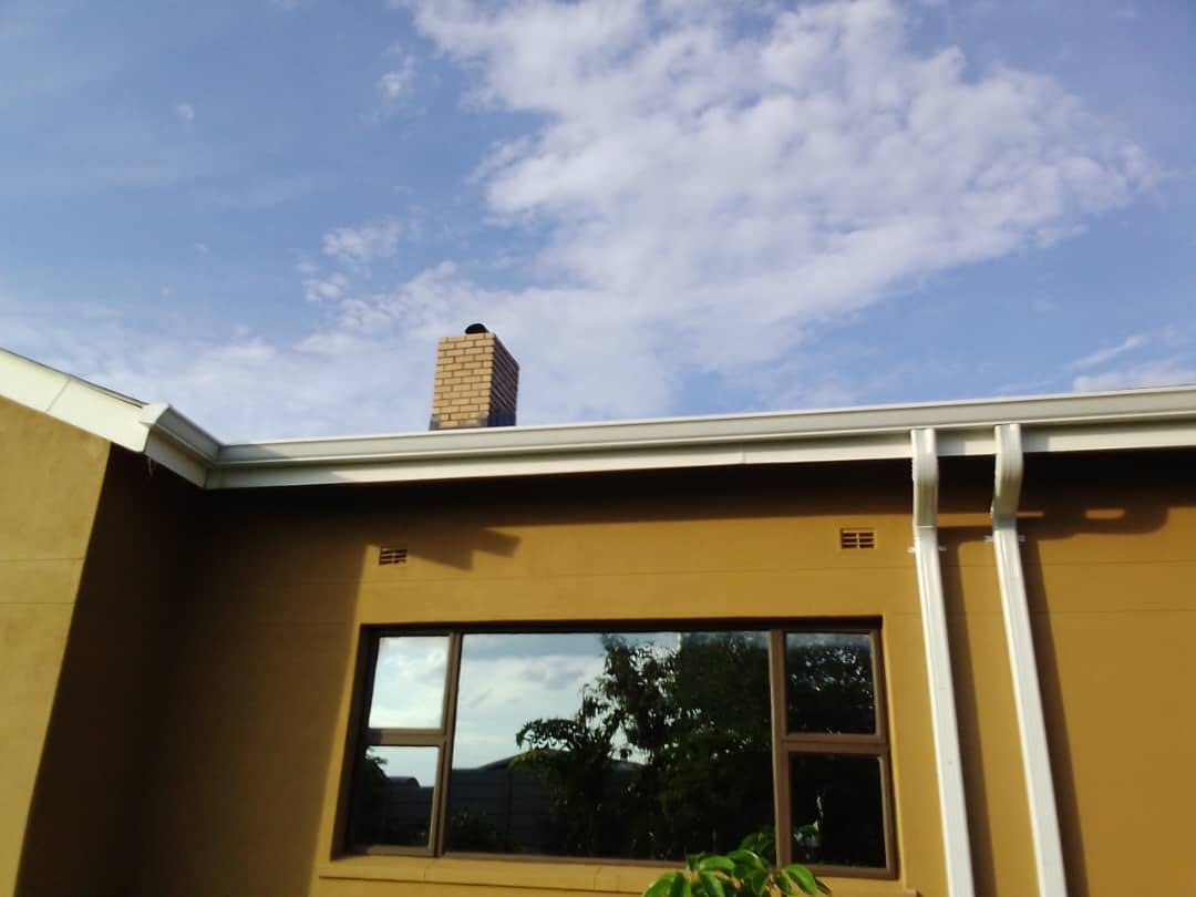 Seamless gutter and paired downpipes along a residential roofline