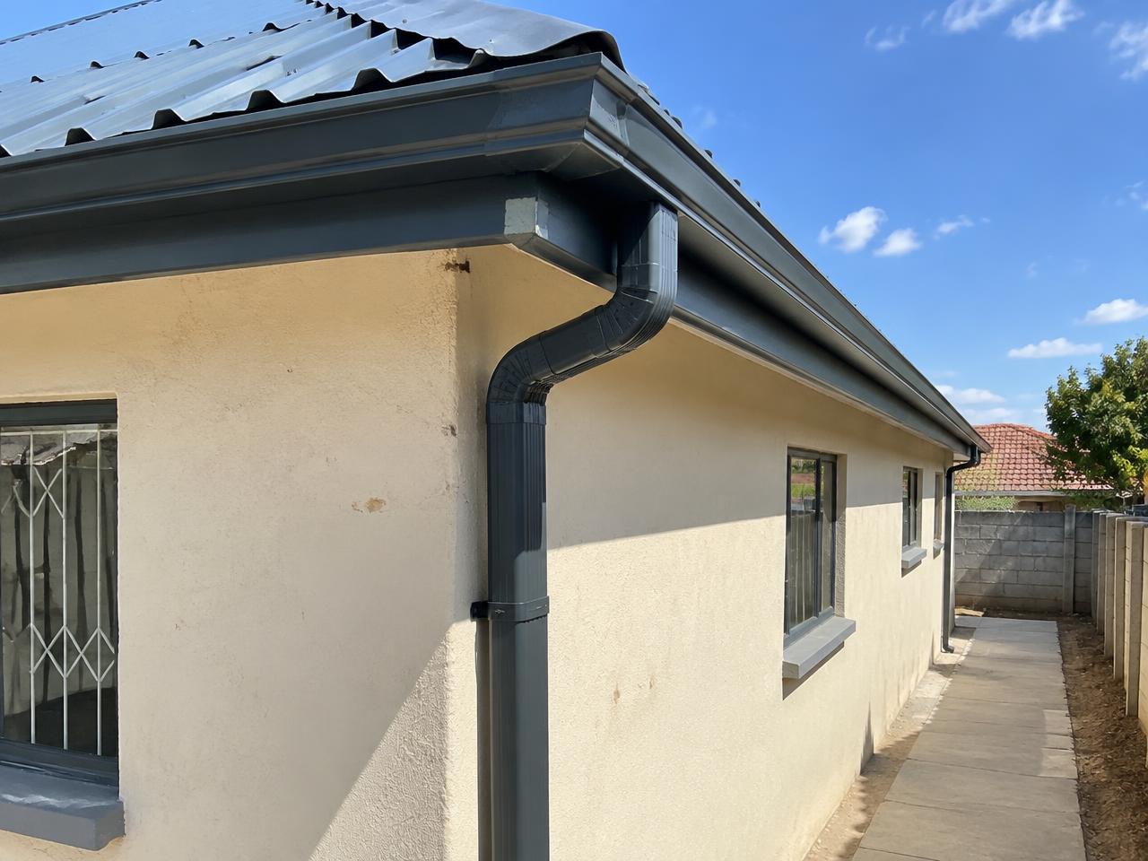 Charcoal gutter and downpipe fitted beneath a metal roof